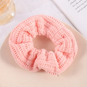 Detail of pink knitted scrunchie texture on a desktop with elegant lifestyle props