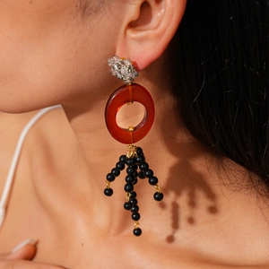 Détail de boucles d'oreilles en résine avec perles ambrées et pampilles à franges noires