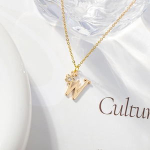 Detail of golden letter W pendant with zircon flower and delicate link chain