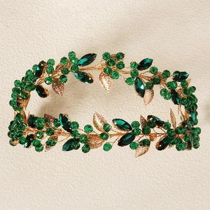 Detailed view of baroque gold headpiece with green crystals and floral metal leaves