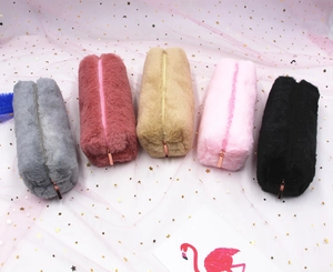 Flat lay of five colorful plush pencil cases in grey, pink and black with soft fur texture
