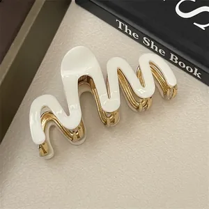 Detail of wavy acetate shark hair clip with cream white texture and golden metal base