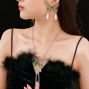 Detail of green butterfly necklace and earrings set with pearl tassels on a model