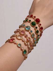 Detail of luxury gold bracelets featuring colorful Czech glass stones on a model wrist
