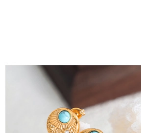Detailed macro view of gold sunburst earrings with turquoise stone and zircon accents