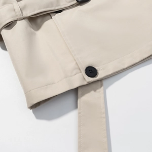 Gros plan détaillé de l'ourlet du trench beige avec bouton noir et coutures fines