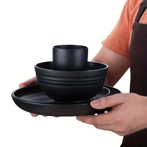 Detailed view of matte black 16-piece plastic dinnerware set being held by hands