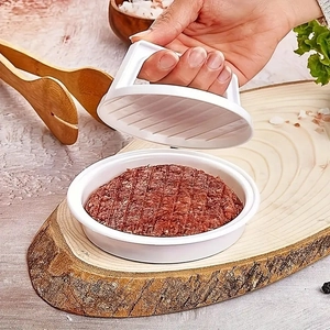 White plastic hamburger patty press mold with handle on a natural wooden board