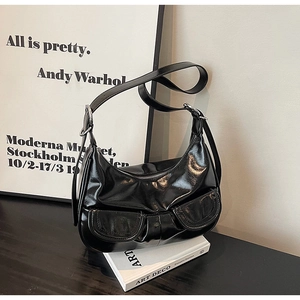 Detail of black crescent shoulder bag with glossy finish and double front pockets
