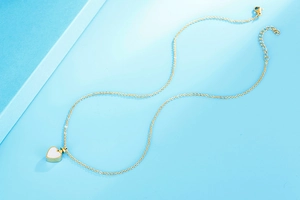 Vue détaillée du collier coeur doré avec pendentif en nacre blanche et fermoir mousqueton