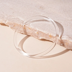 Gros plan du bracelet circulaire en acrylique transparent sur une pierre beige texturée