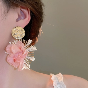 Close-up of model wearing pink oversized chiffon flower drop earrings with gold finish