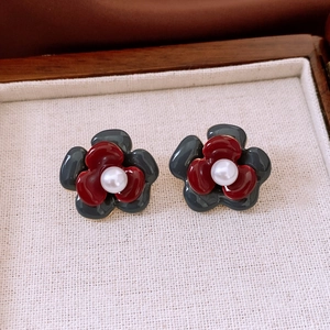 Detail view of double-layered floral earrings with white pearl center and red grey petals