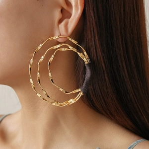 Detail of multi-layered golden twisted hoop earrings with black wire wrap accents