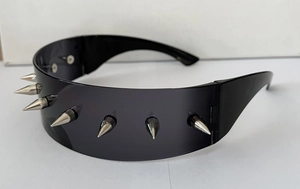 Detail of futuristic wrap-around sunglasses featuring silver metallic studs and dark lenses