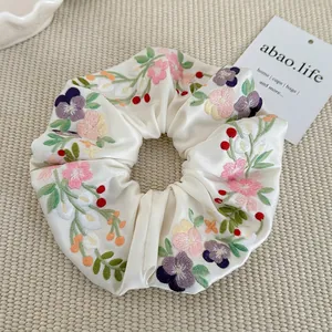 Floral embroidered satin scrunchie with pastel flowers on beige silk fabric