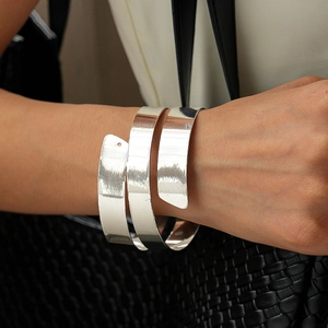 Macro shot of polished silver triple-layer spiral cuff bracelet on a woman's wrist