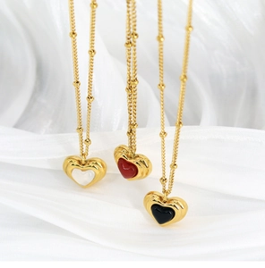 Detailed view of layered heart necklaces in black, red and white on white silk fabric