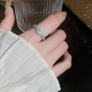 Close-up of a silver geometric zircon ring with a square halo diamond setting