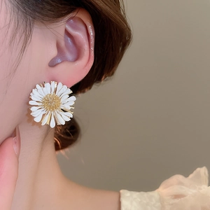 Detail shot of 3D white daisy stud earring with golden stamen on a model's ear