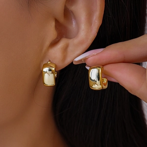 Macro shot of polished gold chunky C-shaped hoop earrings showcasing glossy mirror finish
