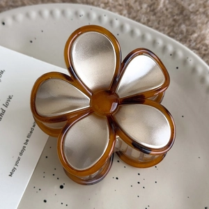 Detail of amber vintage floral acrylic hair claw clip with golden champagne petals