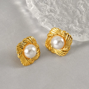 Macro shot of vintage gold square earrings with embossed texture and inset pearl