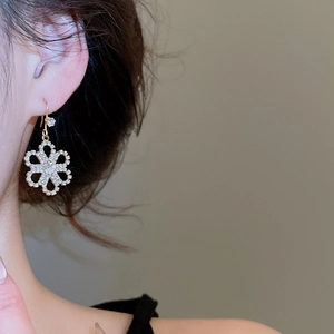 Close-up of gold flower earrings with sparkling rhinestones worn by a model
