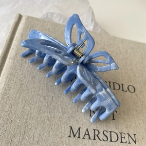 Detail of a blue marble butterfly hair claw clip with golden spring on a book