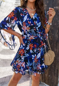 Detail of dark blue floral chiffon dress with ruffled cuffs and tie-waist on a model