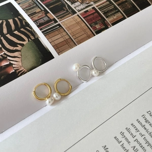 Elegant pearl earrings in gold and silver finish placed on an aesthetic magazine page