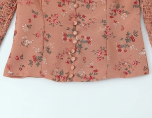 Détail d'une blouse en mousseline fleurie vieux rose avec boutons recouverts de tissu