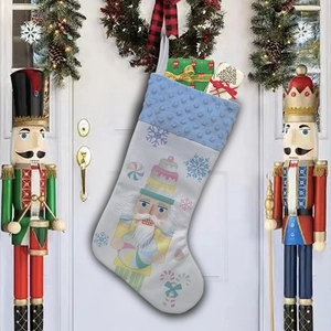Detailed view of a white Christmas stocking featuring a Nutcracker soldier and gift boxes