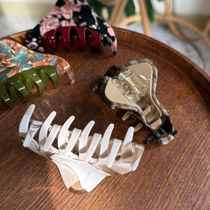Close-up of four assorted marble pattern hair claw clips on a round wooden tray