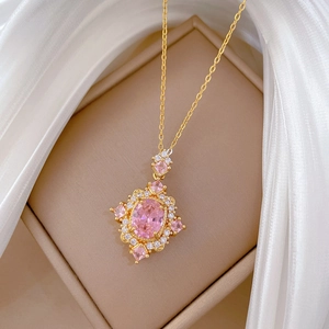 Detail of pink oval stone pendant with sparkling gemstones on gold chain necklace