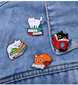 Detailed view of four cartoon cat enamel pins styled on dark blue denim fabric