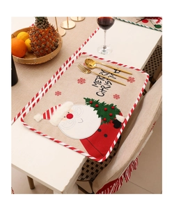 Close-up of embroidered Santa Claus placemat with festive cutlery on a white table