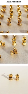Detail shot of golden bow earrings with vertical stripe texture and black zircon center