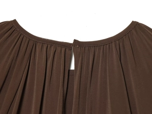 Macro detail of brown blouse showing pleated neckline and slit back design