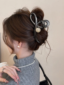 Detail of a large gunmetal alloy hair claw clip with pearls on a model back view