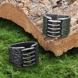 Close-up of vintage silver and charcoal black textured stainless steel rings on bark