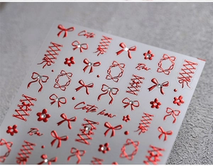 Detail of red metallic 3D bow nail stickers with Cute Bow text on transparent sheet