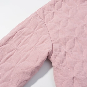 Detailed view of pink quilted fabric texture with diamond stitching on chic jacket