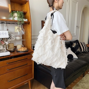 Close-up of white bohemian fringe tote bag in soft canvas texture on a female model