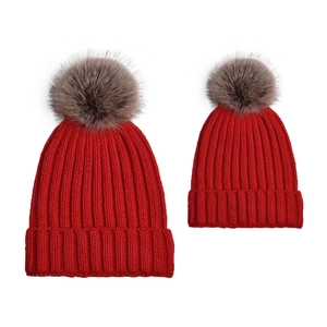 Detail of red matching parent-child knit hats with fluffy pom-poms for winter warmth