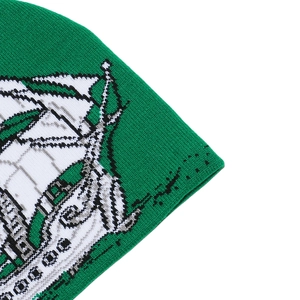 Détail du bonnet en tricot vert montrant le motif jacquard de voilier et la texture