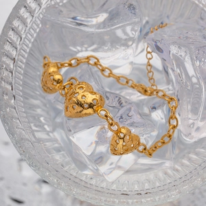 Elegant gold hollow heart pendant bracelet in stainless steel on ice texture background