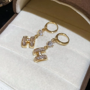 Macro detail of 14K gold plated H letter earrings with cubic zirconia and pearls