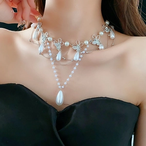 Close-up of triple-layered pearl necklace with crystal butterfly and drop pendants