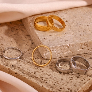 Minimalist 18K gold and silver plated stainless steel rings on a premium textured display